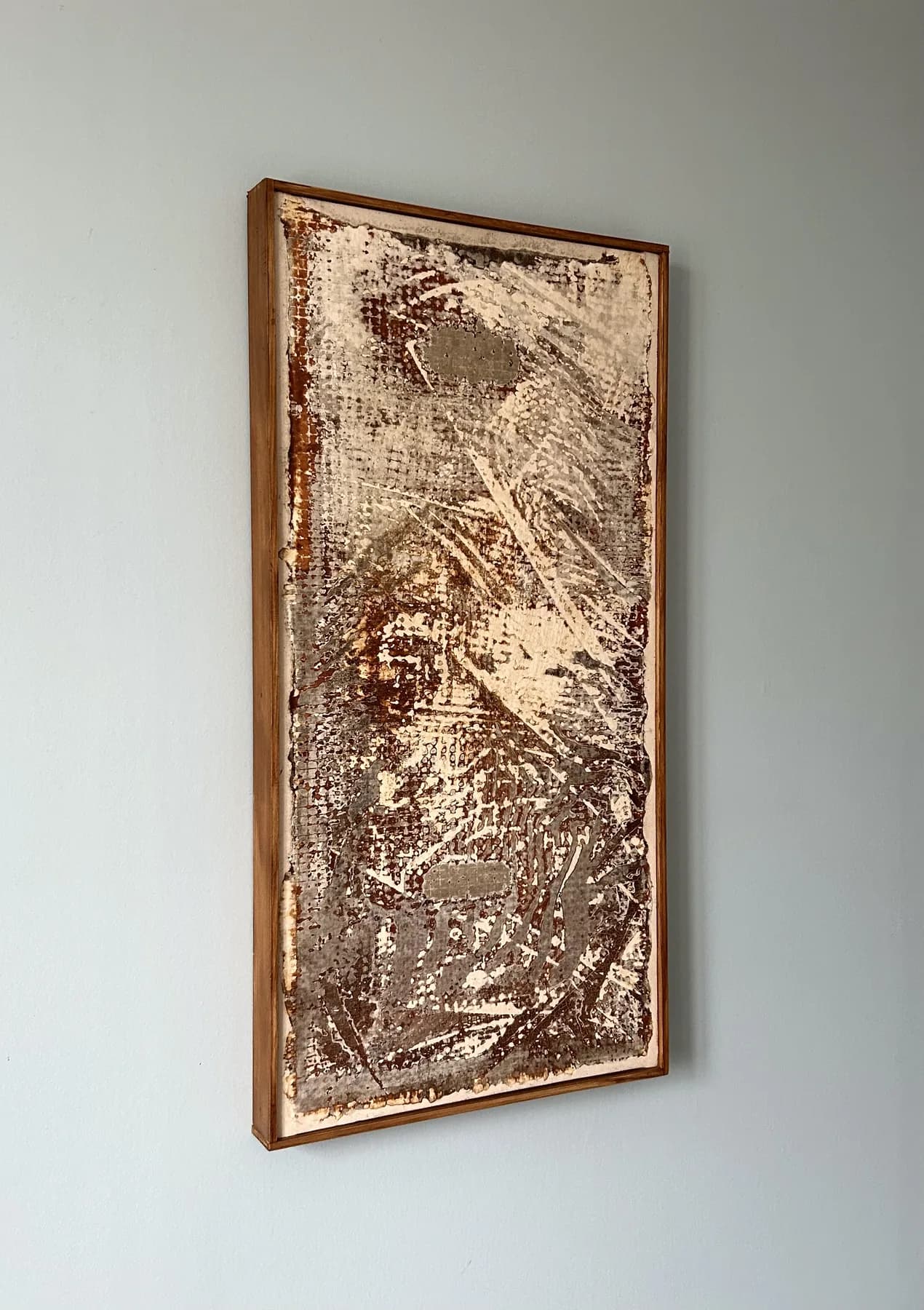 Panel with brown speckled and swept texture in a copper-coloured frame, hanging on a pale grey wall.