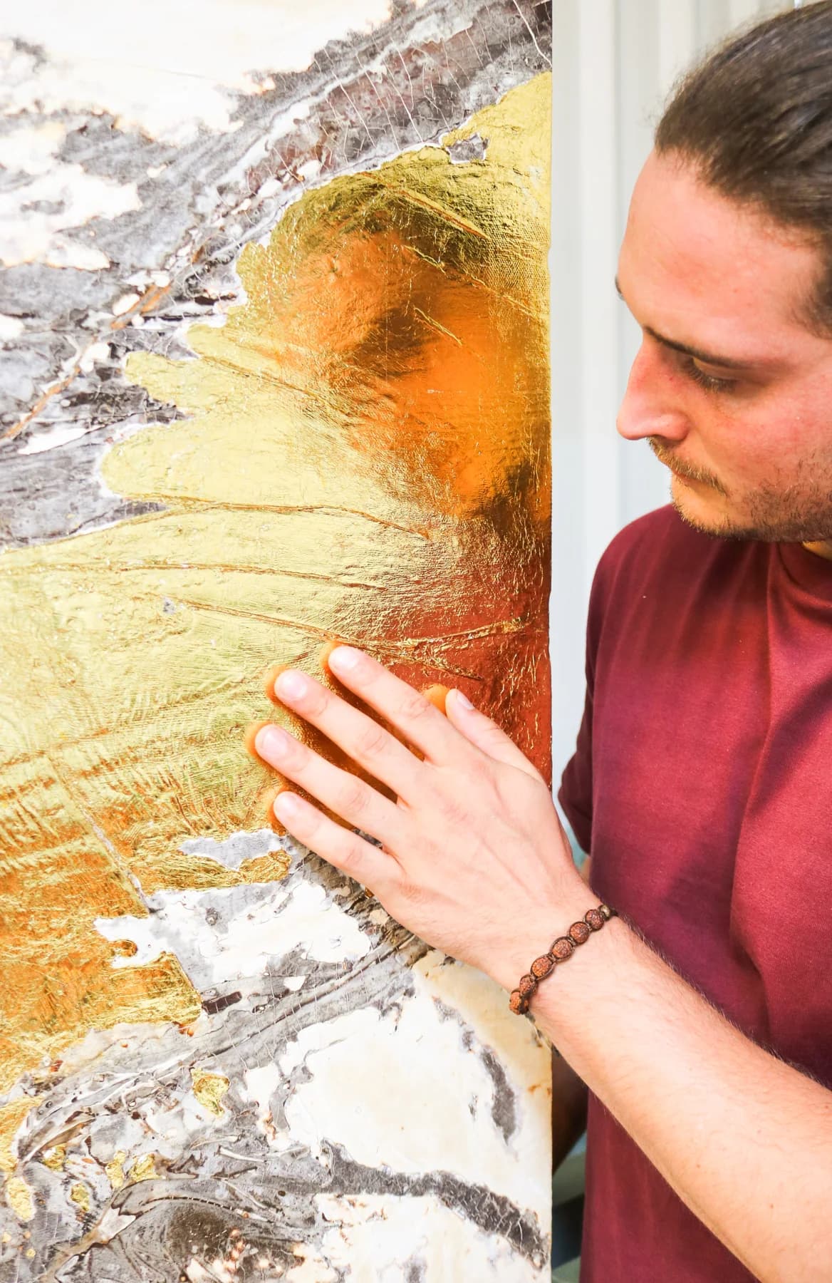 Andy Cartier touching the edge of a panel where the gold leaf glows orange in the light.