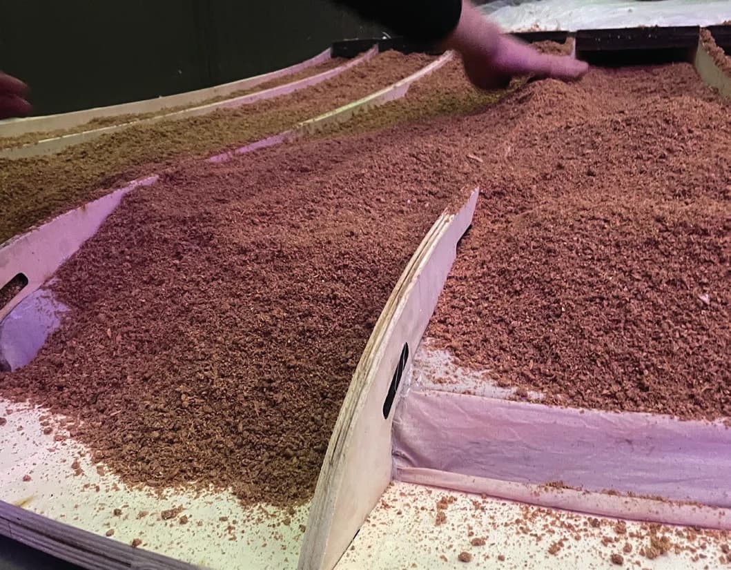 Reddish-brown substrate packed into fabric-lined sections between curved plywood ribs.